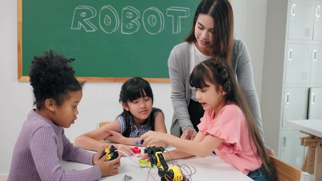 Smart primary students grouping to learning robot free electives with female teacher in classroom. Caucasian teacher female teach childrens assemble robot in science subject at elementary school.