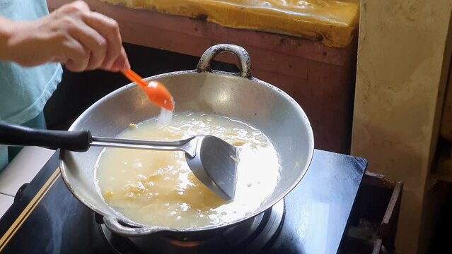 Adding a spoonful of salt and a spoonful of MSG into mixed egg or beaten egg or whisked egg in the frying pan on the lit black stove, just like making scrambled egg. high angle shoot.