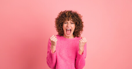 Shocked young woman showing stretched hands on pink background