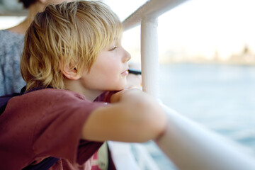 Cute blonde preteen tourist boy is traveling by boat or ferry on the sea. Family vacations on ocean...