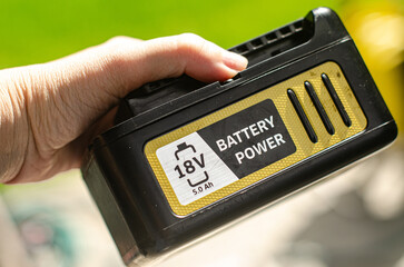Hand hold the battery for electric cordless lawn mower. High quality photo