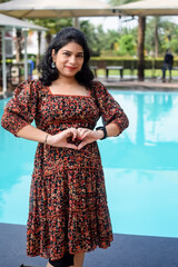 A pregnant Indian lady poses for outdoor pregnancy shoot and hands on belly, Indian pregnant woman puts her hand on her stomach with a maternity dress at society park, Pregnant outside maternity shoot