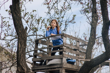 Beautiful pensive girl, inspired dreamy child teenager stands on a wooden bridge outdoors in...