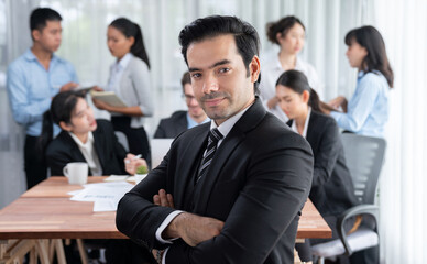 Portrait of happy businessman looking at camera with motion blur background of business people...