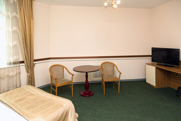 Spacious hotel room with furniture green carpet on the floor.
