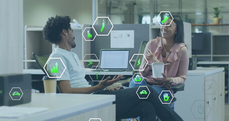 Image of icon in hexagons over diverse coworkers eating food and discussing on desk in office