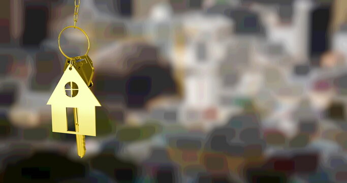 Image of gold house key fob and key, hanging in front of blurred city view