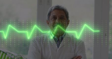 Image of heart rate monitor against portrait of biracial senior male doctor smiling at hospital - Powered by Adobe