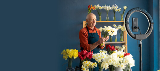 A man who owns flower shop films on camera how to arrange bouquet.