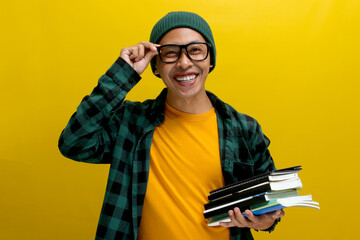 An excited young Asian student, dressed casually in a beanie hat and casual clothes, adjusts his...