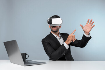 Skilled business man looking at data analysis while sitting at table with laptop and wearing VR glasses. Project manager working by using virtual reality system or connecting at metaverse. Deviation.