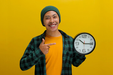 An excited young Asian man, dressed in a beanie hat and casual shirt, enthusiastically holds a...