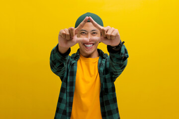 Young Asian man, dressed in a casual shirt and wearing a beanie hat, is creating a triangle shape with his hands, symbolizing the concept of environmental protection, recycling, and reusing