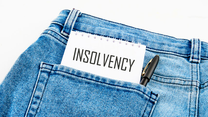 Debt relief concept. A word INSOLVENCY on a notebook from a pocket next to a pen