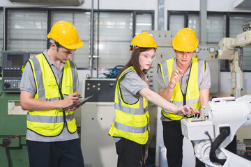 A Group of engineer are examining machine robot arm with smart tablet. Installation indoor industrial factory. Technician coworker check for repair maintenance electronic operation with remote system