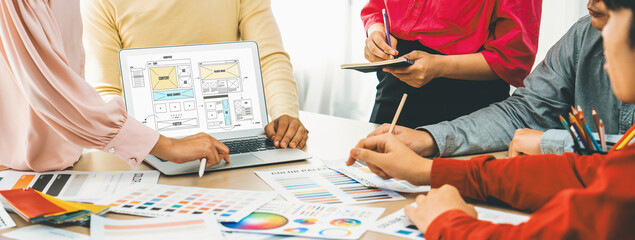 Cropped image of interior designer team discuss the material color while laptop displayed website wireframe designs for mobiles app and website. Creative design and business concept. Variegated.