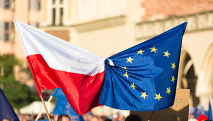 european union flagstied with flag of Poland waves on public demonstartion to support Polish...