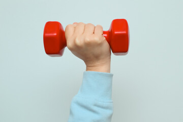 Woman's hand lifting a red dumbbell on a white background