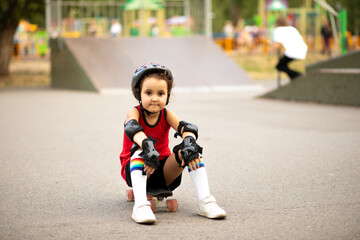 Cute kid girl child with skateboard sitting in a skatepark and smiling. Child performs tricks....