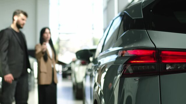 The buyer, a client of a modern car dealership, chooses a car. A dealer talks about a new model of a modern electric car. The concept of test drive, buying an electric car or renting it.