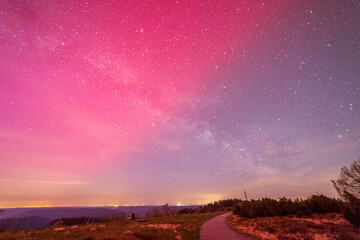 milky way above hornisgride in Baden-württemberg, germany with slight red northern lights on the sky