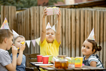 Cute funny nine year old boy celebrating his birthday with family or friends in a backyard....