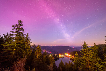 Milky way above Mummelsee in black forest in germany from hornisgrinde with slight red northern...