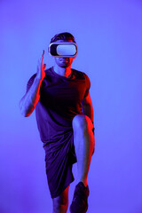 Caucasian smart man jogging while wearing VR goggle with neon light. Happy person with casual cloth running or exercising while using virtual reality headset. Innovation technology concept. Deviation.