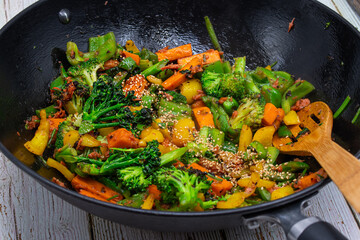 Vegan stir fry consisting of broccoli, carrot, peppers cooked in steel wok