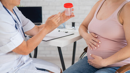 The doctor explains to a pregnant patient how to pass a urine test.