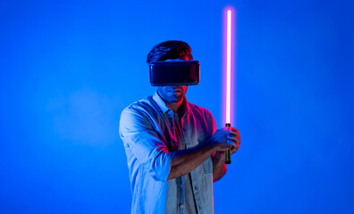 Caucasian man wearing VR glass and moving gesture holding sword. Gamer using future digital virtual...