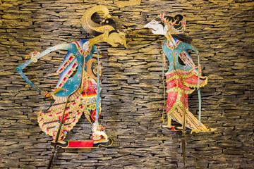 Wayang kulit or Shadow puppets typical of Java, Indonesia, hanging on brick wall with warm light 