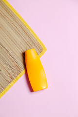 Beach mat and sunscreen on pink background. Beach concept. Feminine concept. Space for text.
