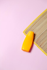 Beach mat and sunscreen on pink background. Beach concept. Feminine concept. Space for text.