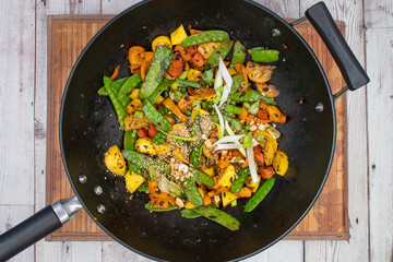 Snow peas, pepper, carrot and squash stir fry in cast iron wok. Served along with Asian noodles.