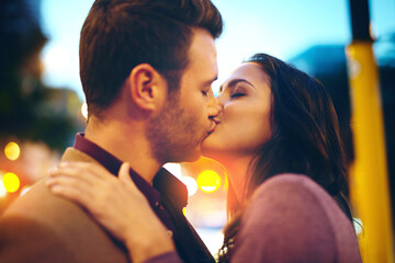 Night, kiss and couple on date, street and bokeh of light, city and anniversary of man with...