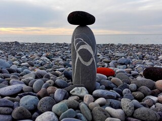 Stones pyramid or tower on pebble beach symbol stability zen harmony balance. Pebble stone black tower or pyramid pile on sea. Stone Pyramidal tower of pebbles. Stack of different pebbles and stones