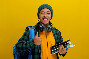 Confident Asian student in beanie and casual clothes, carrying backpack and headphones, Holding a...