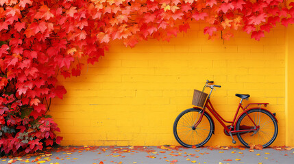 A red bicycle on a yellow brick wall with striking colors of maple leaves on the edge of the wall during Fall season