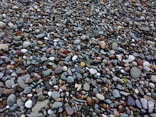 Perspective rounded Sea Pebble stones and multicolor rocks on beach natural abstract pebble stone texture or background. Random small pebble stones. Close up colorful Pebble stones or gravel on coast