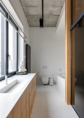 Bathroom with sink, toilet, and window features wood cabinetry and flooring