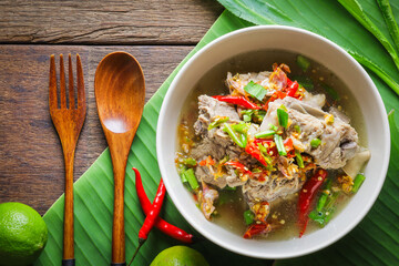 Thai food, Spicy Pork Soup, tom leng, in a white bowl placed on a wooden table is a highly popular spicy food. Popular authentic Thai food concept.