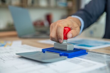 A person stamping a document with a red stamper