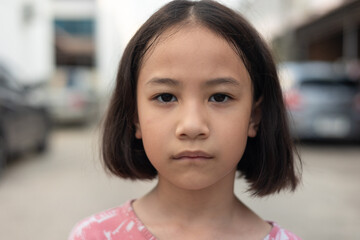 Face and eyes closed up of adorable Asian kid girl who is looking and staring outdoor with serious...