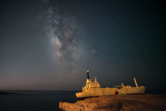 The wrecked ship under night sky with milky way
