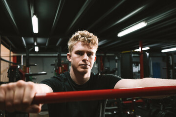 Handsome male athlete looking focused to the camera, holding onto a barbell