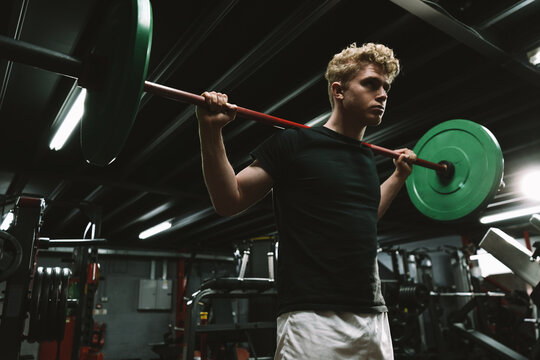 Low angle shot of a sportsman doing barbell squats at crossfit gym