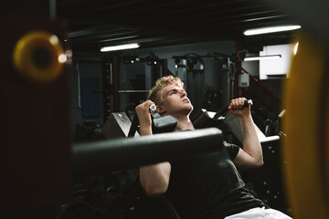Young man looking focused, working out on hack squat machine