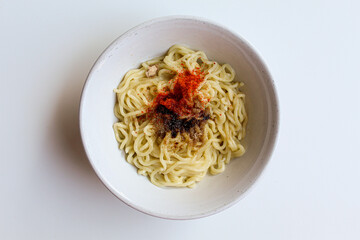 A serving of instant noodles with powder seasoning on top, on white bowl, isolated on white background, flat lay or top view