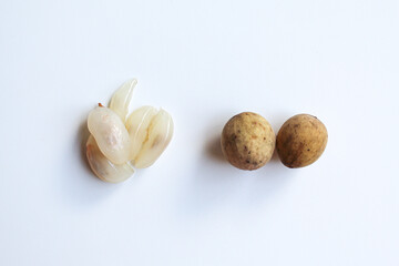 Fruit of Lansium domesticum var duku, known as duku, or langsat, or lanzones, before and after peeled. Isolated on white background, flat lay or top view